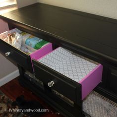 the drawers are open on the dresser in the room that is decorated with pink and white paper