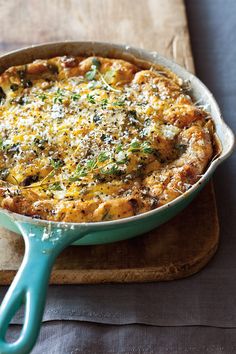 a casserole with cheese and herbs in a blue dish on a wooden board