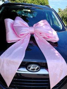 a pink bow tied to the hood of a car