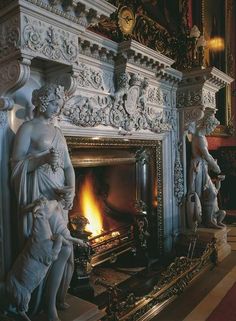 a fireplace with statues around it and a fire place in the middle of the room