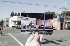 a person holding up an old photo in front of a gas station on the street