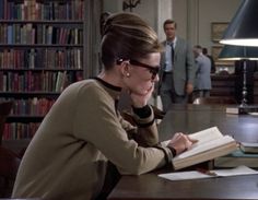 a woman sitting at a desk in front of a book