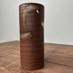 a brown vase sitting on top of a wooden table