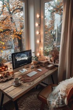 a desk with a computer on it in front of a window filled with fall leaves