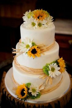 a three tiered cake with sunflowers on top