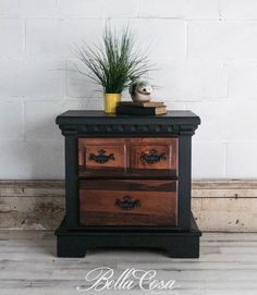 an old dresser with two drawers and a potted plant on top