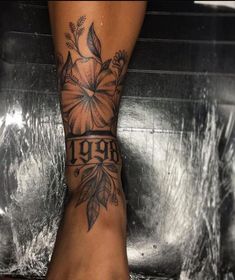 a woman's foot with a flower tattoo on her left leg and the words 1909 written in black ink