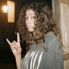 a woman with curly hair making the peace sign