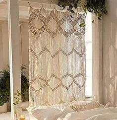 a white bed sitting under a window next to a potted plant