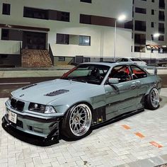 a silver car parked in front of a tall building