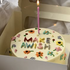 a birthday cake with the words am ash on it and a lit candle in the middle