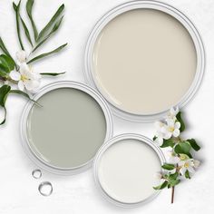 three different shades of paint with white flowers and greenery on the top right side