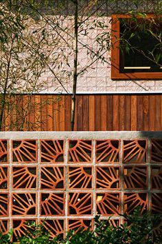 a wooden fence next to a building with a window on it's side and trees in the background