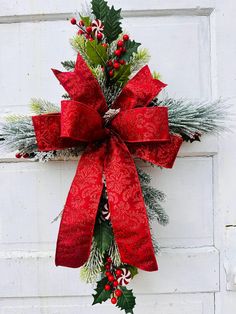 a christmas wreath with holly, mist and candy canes hanging on a white door