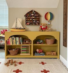 there is a yellow book shelf with books and toys on it in the children's room