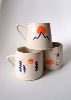 three mugs with designs on them sitting next to each other in front of a white background