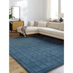 a living room with a blue rug on the floor and a white couch in front of it