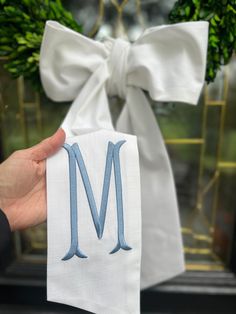 a hand holding up a napkin with the letter m on it and a bow tied around it