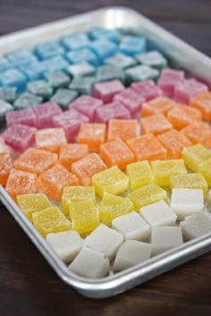 a tray filled with different colored marshmallows on top of a wooden table