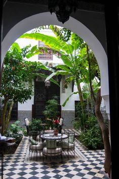 an outdoor dining area with black and white checkered tile flooring, potted plants and trees