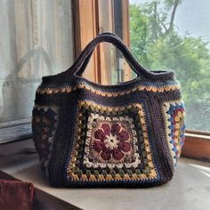 a crocheted purse sitting on top of a window sill next to a window