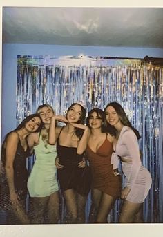 a group of young women standing next to each other in front of a wall with streamers