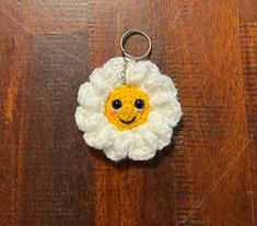 a crocheted keychain with a smiley face in the center on a wooden surface