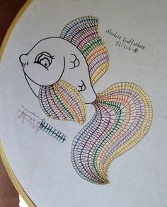 a cross - stitch fish with colorful lines on it's face and tail, in the shape of a circle