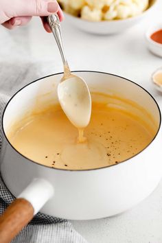 a spoon is being used to stir soup in a white bowl