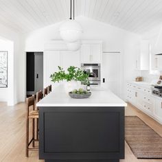 a kitchen with white cabinets and black island