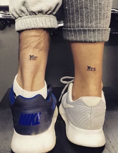 two people with matching tattoos on their feet standing next to each other, both wearing sneakers