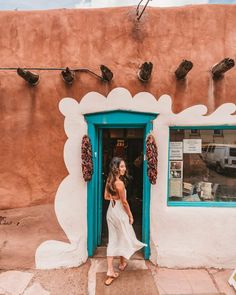 a woman standing in front of a doorway with birds on the wall and windows above her