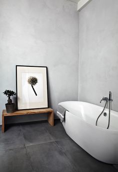 a white bath tub sitting next to a wooden stand with a plant on top of it