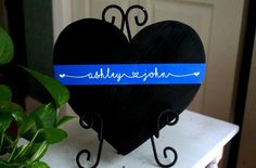 a black heart with blue ribbon and name on it sitting next to a potted plant