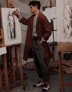 a man standing in front of an easel with his hands on the easel