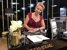 a woman sitting at a desk in front of a black piano with writing on it