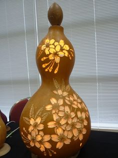 a decorative vase sitting on top of a table next to a window with blinds behind it