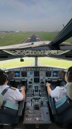 two pilots are sitting in the cockpit of an airplane looking at the runway from inside