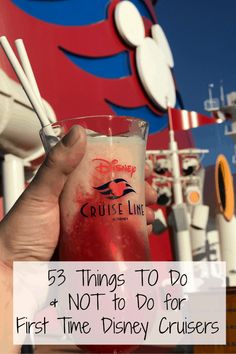 a hand holding a drink with the disney cruise line sign in the background