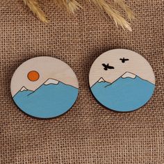 two wooden buttons with mountains and birds on them