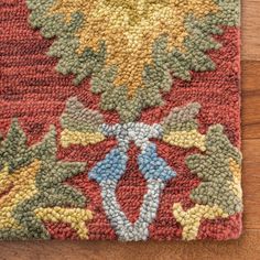 a close up of a rug on a wooden floor with an orange and yellow design