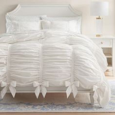 a white bed with ruffled sheets and pillows