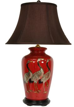 a red lamp with two birds painted on it and a brown shade over the top