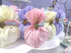 several small bags with flowers on them are sitting on a white tablecloth covered cake