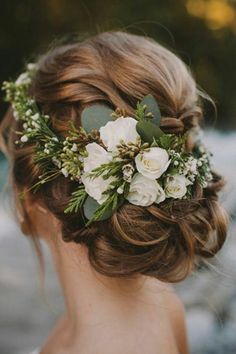 a woman with flowers in her hair is looking at the water and rocks behind her