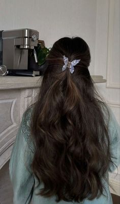 the back of a woman's head with long dark hair, sitting in front of a fireplace