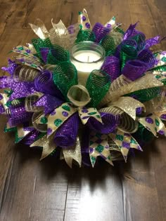 a candle is sitting on the floor next to a purple and green wreath