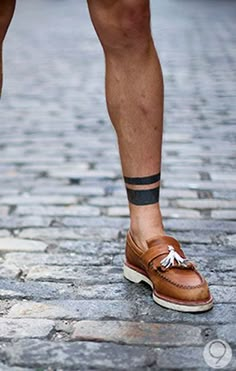 a man in brown shoes standing on cobblestone street