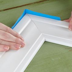 two hands are holding the edge of a white frame