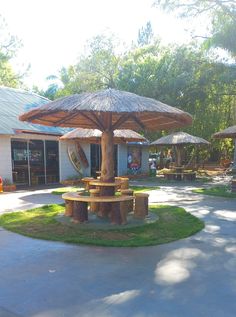 there is an umbrella in the middle of this lawn area with tables and chairs around it